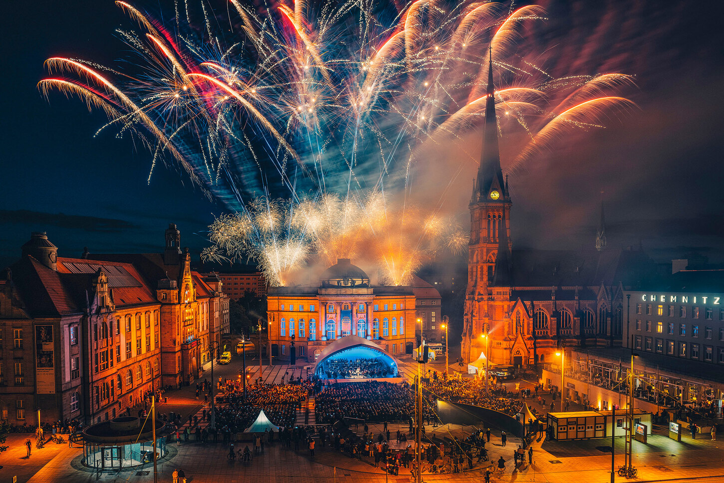 Ein großer Platz mit Feuerwerk im Hintergrund.